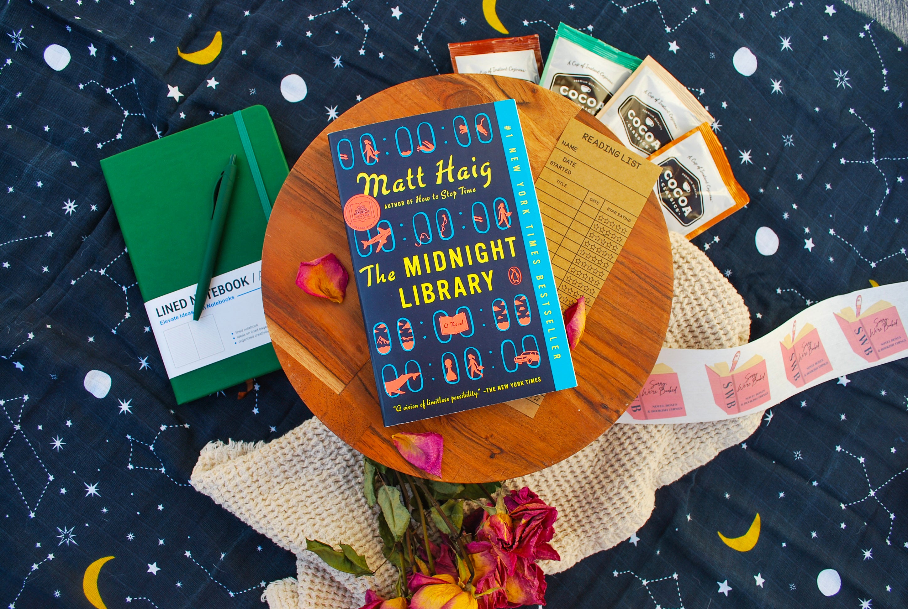 Book titled 'The Midnight Library' by Matt Haig on a wooden table with a starry night background